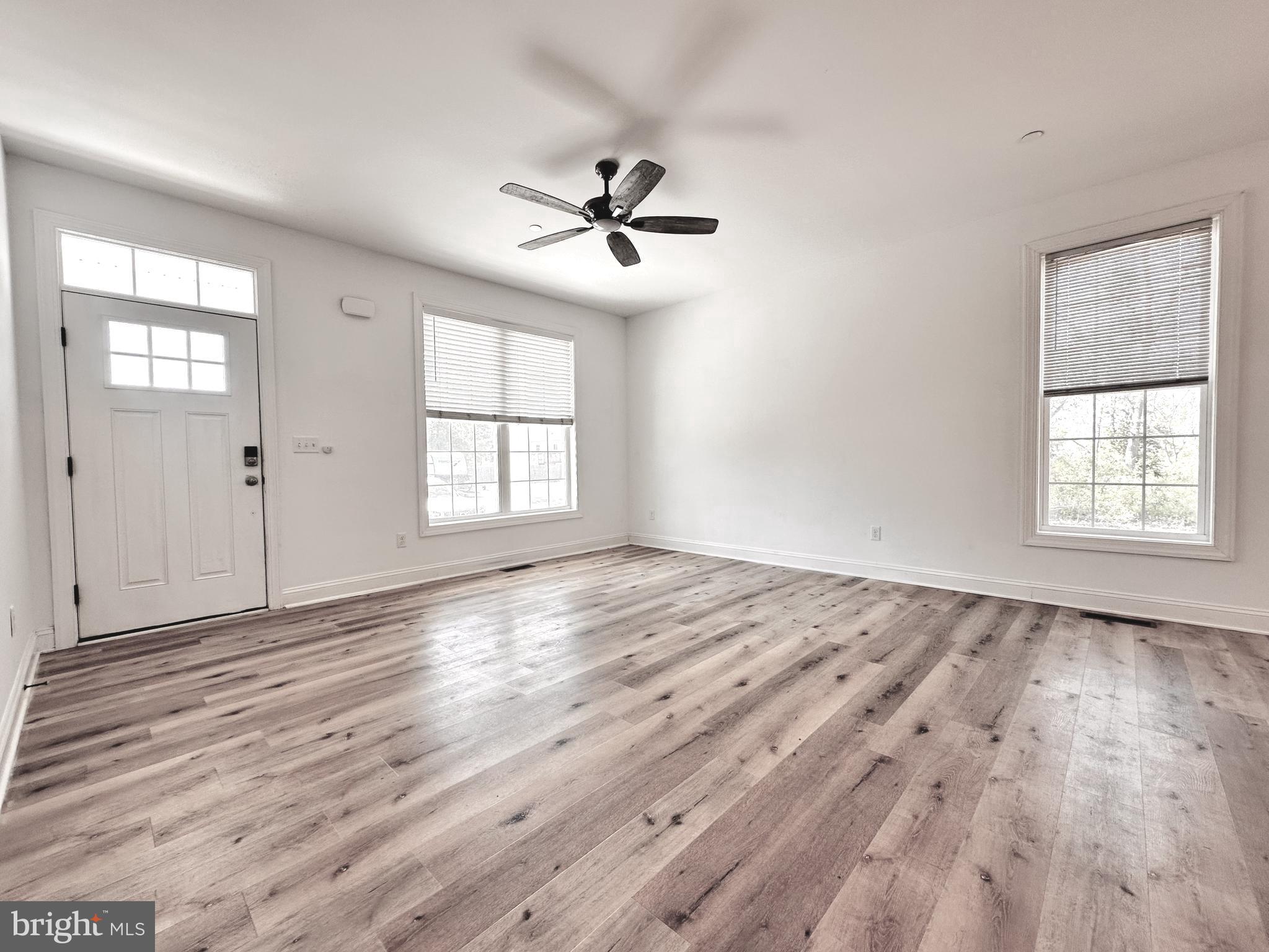 102 Pine Street Crumpton, MD 21628 - Photo 10 of 31 an empty room with wooden floor ceiling fan and windows