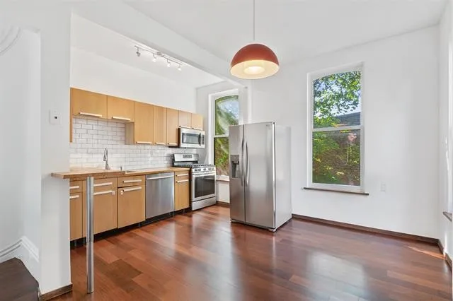 a kitchen with stainless steel appliances granite countertop a refrigerator a stove a sink and a large window