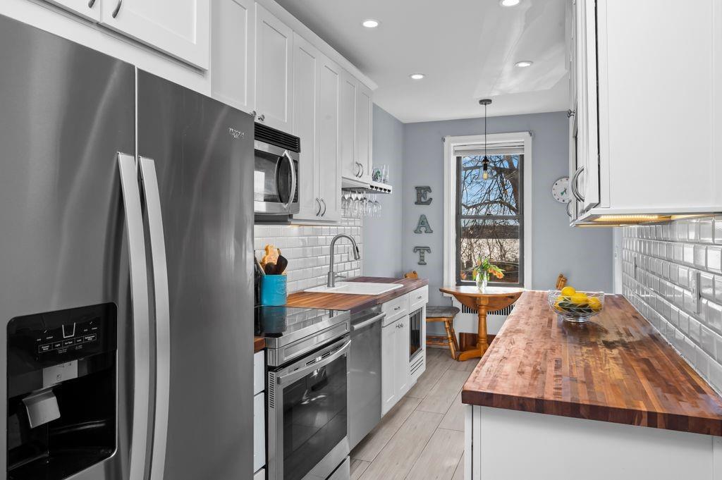 a kitchen with stainless steel appliances granite countertop a refrigerator a stove and a sink