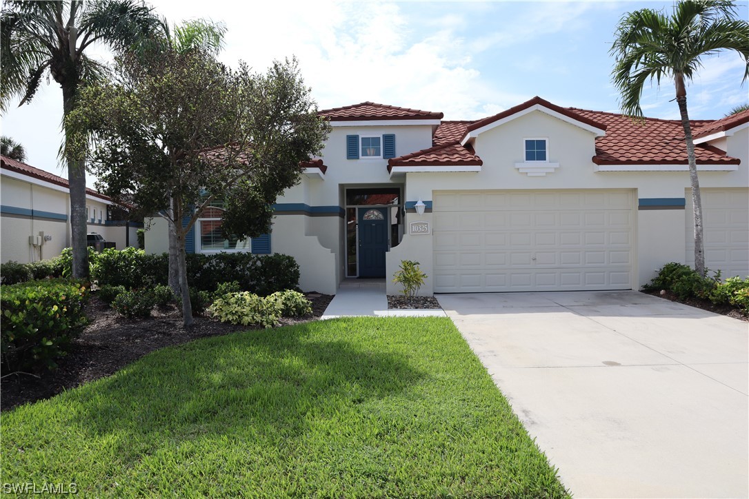 10325 Cape Roman Road, Unit 101 Estero, FL 34135 - Photo 1 of 34 a front view of a house with a garden and plants