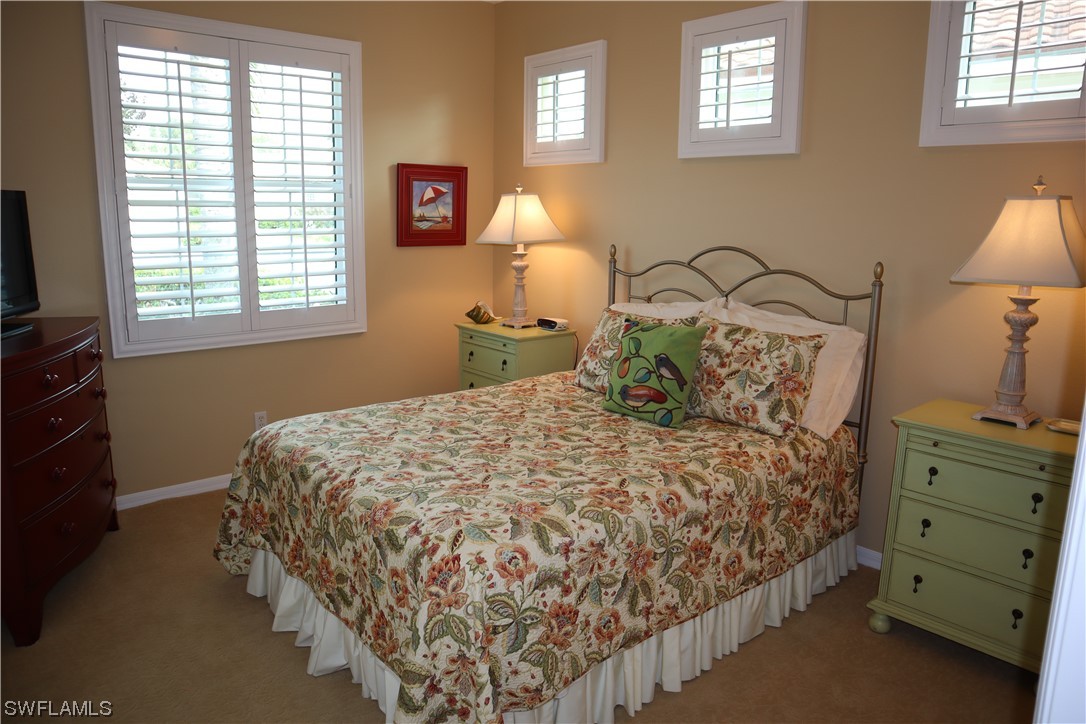 10325 Cape Roman Road, Unit 101 Estero, FL 34135 - Photo 13 of 34 a bedroom with a bed and a lamp on dresser