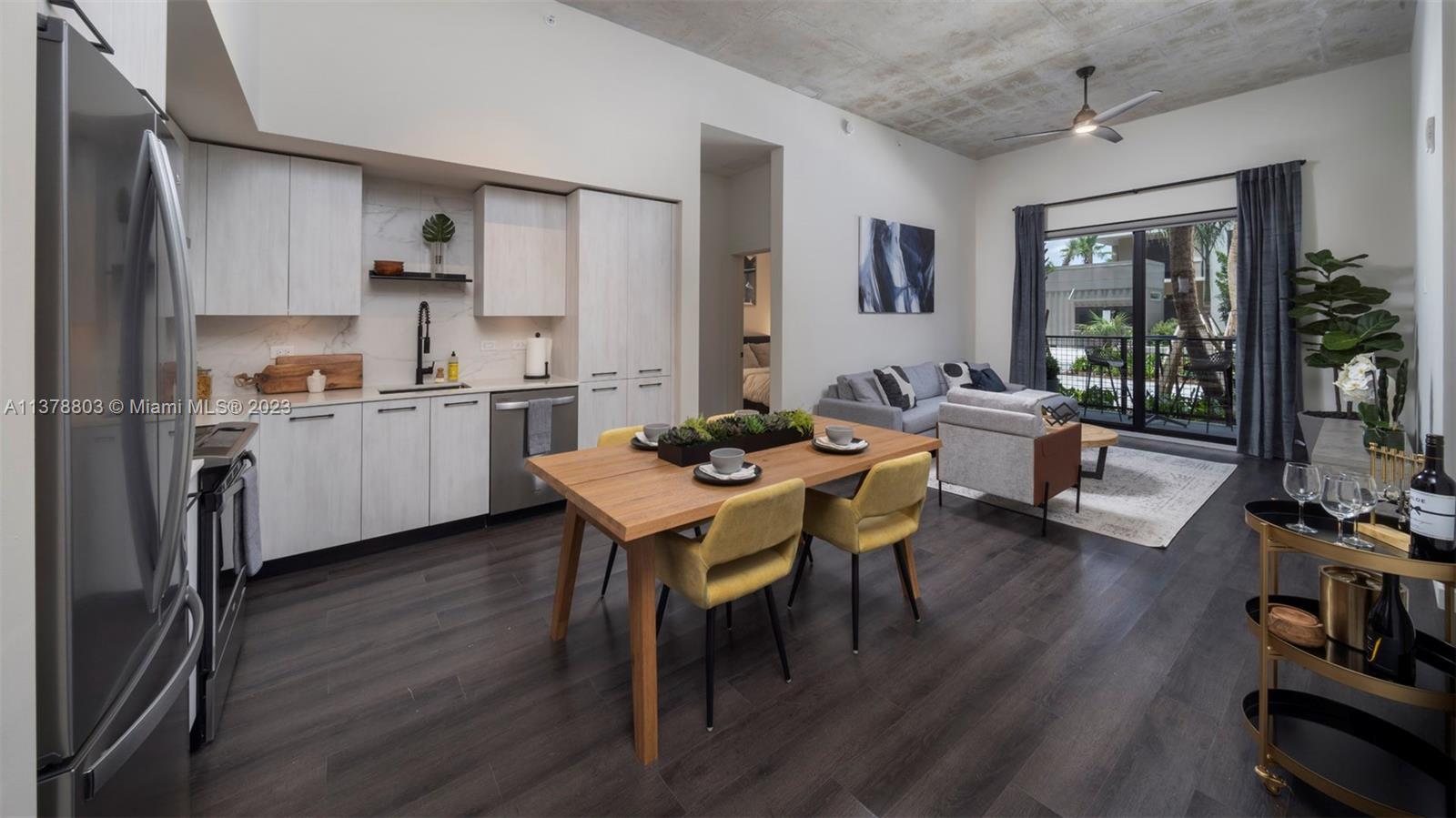 6970 Southwest 40th Street, Unit 442 Miami, FL 33155 - Photo 4 of 23 a open kitchen with stainless steel appliances granite countertop a stove a refrigerator a kitchen island a dining table and chairs with wooden floor