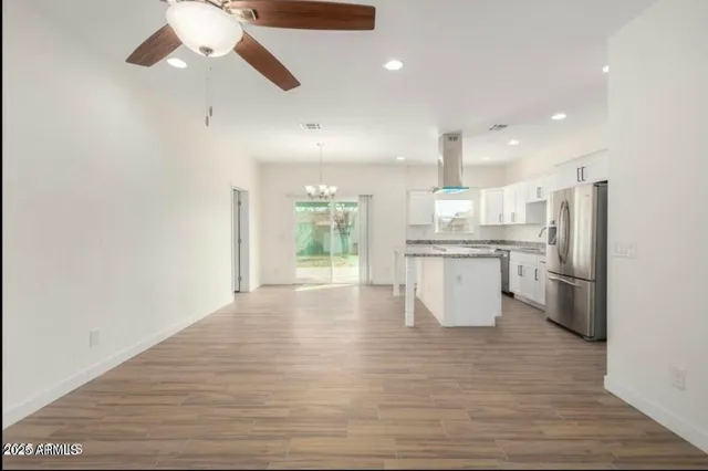 a large kitchen with white cabinets stainless steel appliances and wooden floor