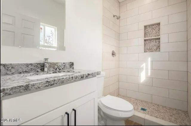 a bathroom with a granite countertop toilet a sink a mirror and shower