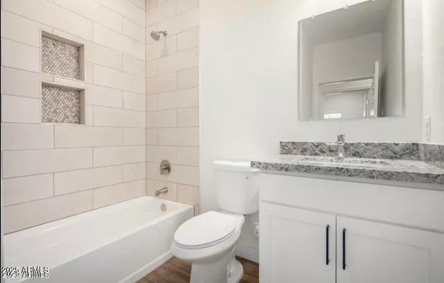 a bathroom with a granite countertop bathtub sink vanity mirror and toilet