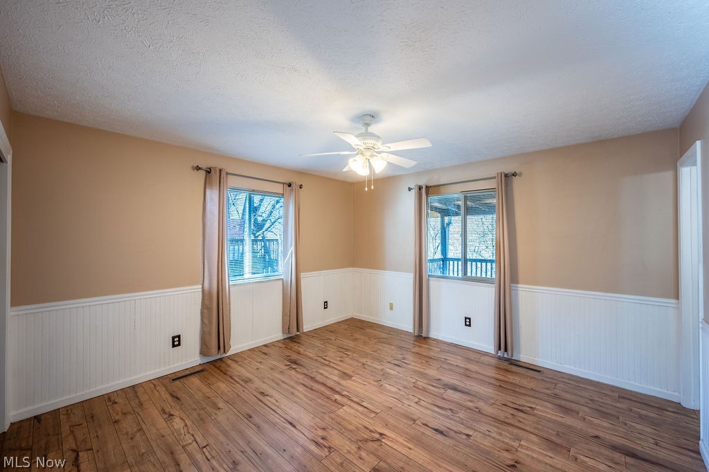 3601 River Road Vienna, WV 26105 - Photo 15 of 40 Spare room featuring wood-type flooring, wainscoting, a textured ceiling, and a ceiling fan