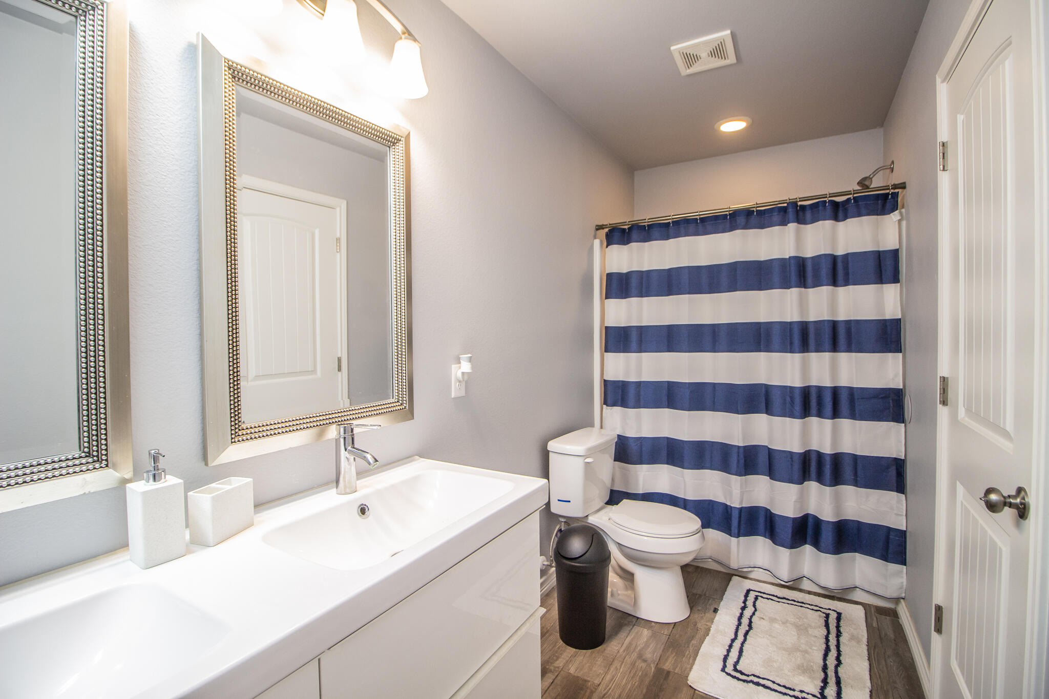 8808 14th Street Lubbock, TX 79416 - Photo 12 of 19 a bathroom with a sink a toilet a mirror and shower curtain