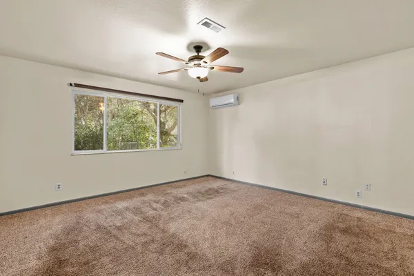 an empty room with a window and a fan