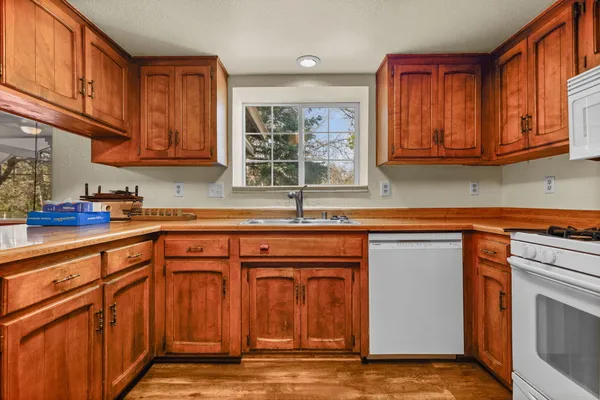 a kitchen with stainless steel appliances granite countertop a sink dishwasher stove and cabinets with wooden floor