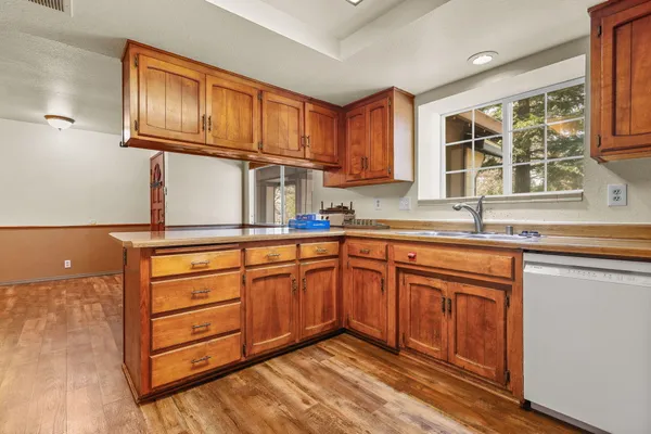 a kitchen with stainless steel appliances granite countertop a sink dishwasher stove and cabinets with wooden floor