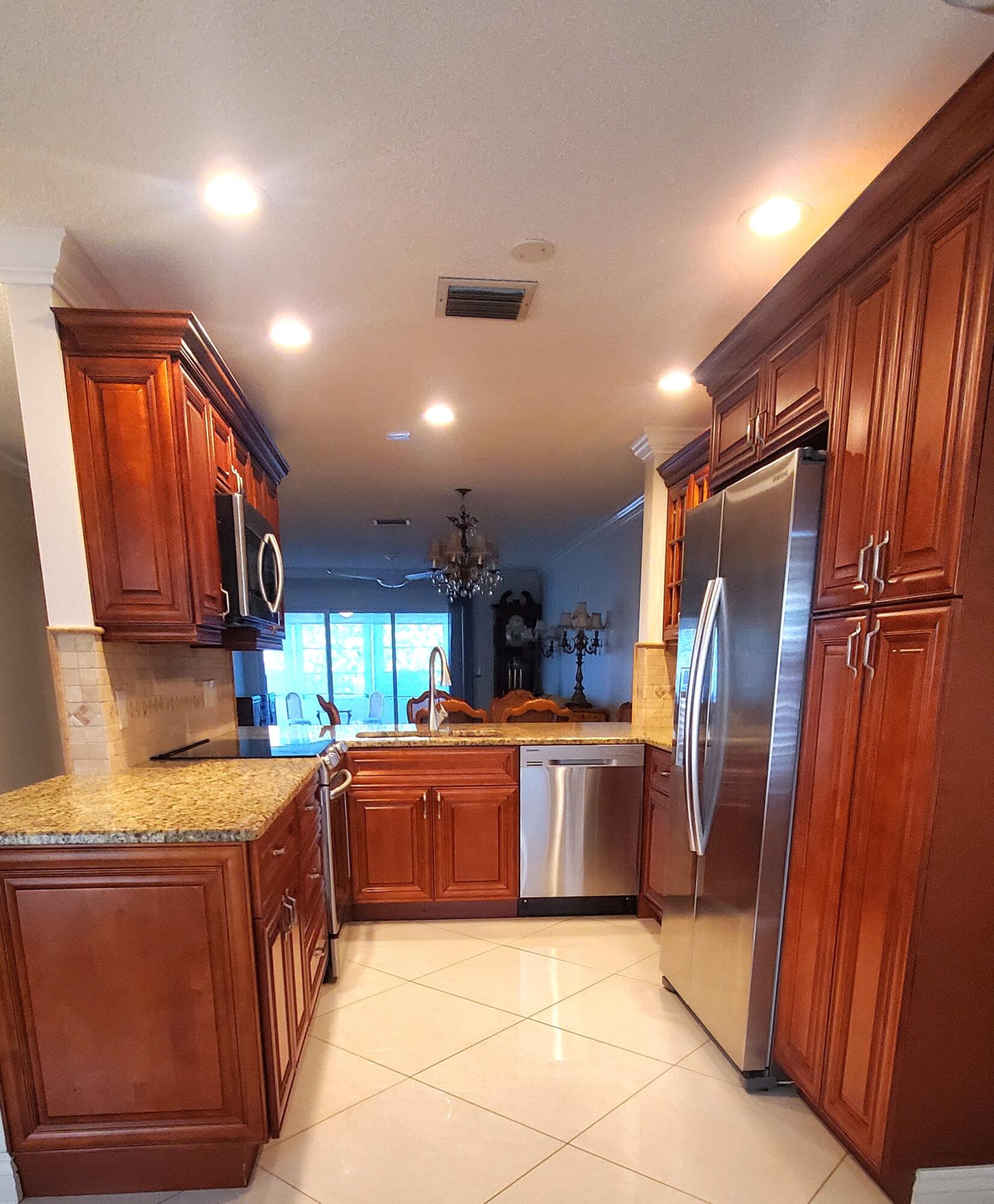 a kitchen with stainless steel appliances granite countertop a refrigerator a sink dishwasher and wooden cabinets