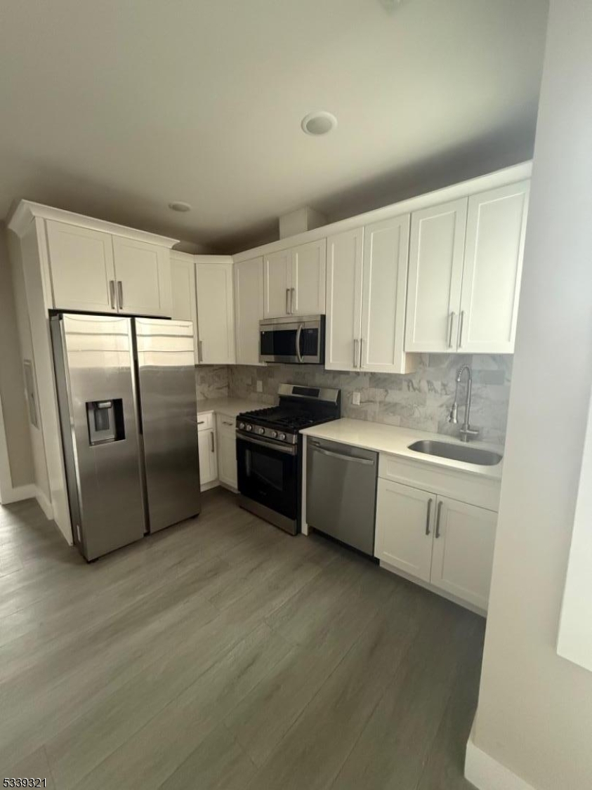 1022 Main Street, Unit 404 Paterson, NJ 07503 - Photo 1 of 7 a kitchen with granite countertop a refrigerator a sink a stove top oven and white cabinets