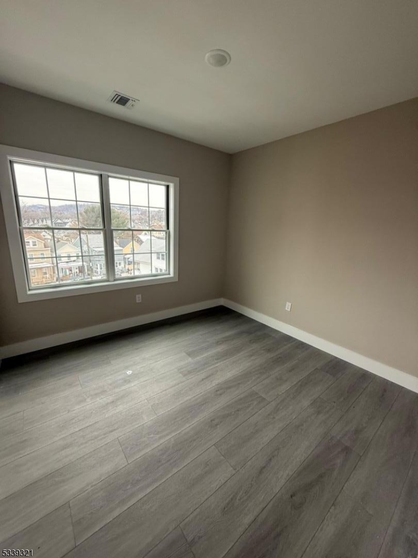 1022 Main Street, Unit 404 Paterson, NJ 07503 - Photo 4 of 7 an empty room with wooden floor and windows