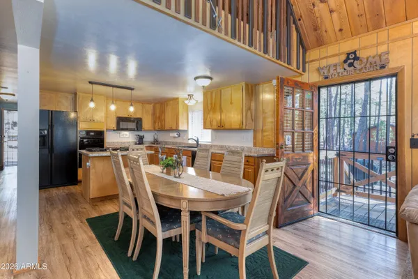 a dining area with stainless steel appliances kitchen island granite countertop a table chairs and a refrigerator