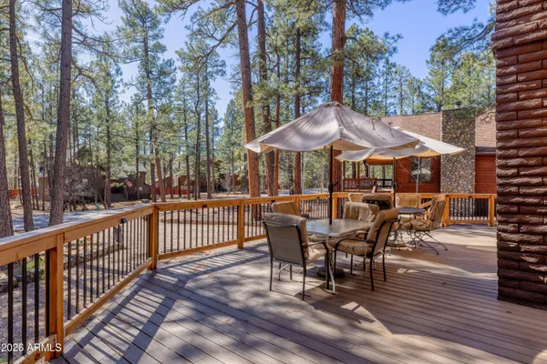 a view of a patio with table and chairs under an umbrella with wooden floor and fence