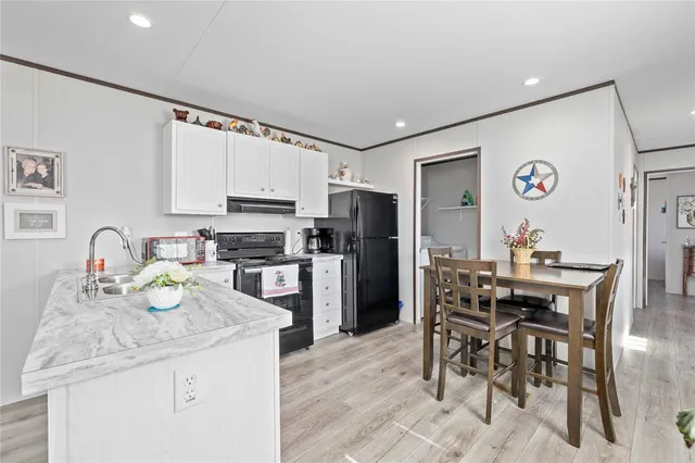 a kitchen with granite countertop a table chairs microwave and cabinets