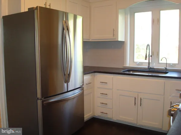 a kitchen with granite countertop white cabinets and black appliances
