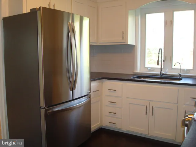 a kitchen with granite countertop white cabinets and black appliances