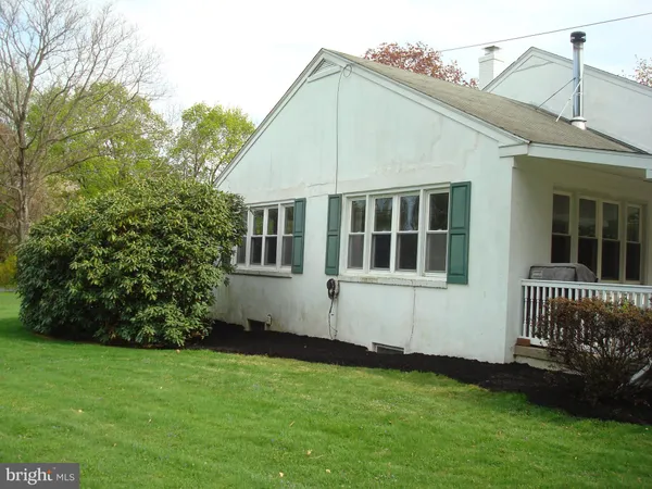 a house that is sitting in the grass with tress in the background