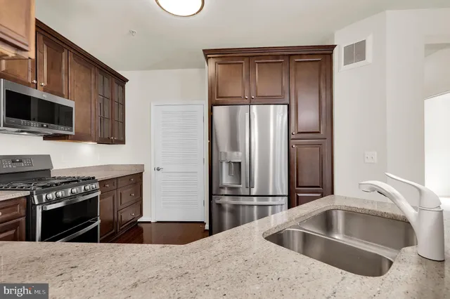 a kitchen with granite countertop a refrigerator and a sink