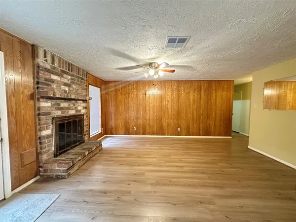a view of an empty room with wooden floor fireplace and a window