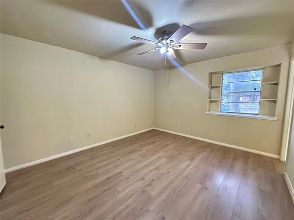a view of an empty room with wooden floor and a chandelier