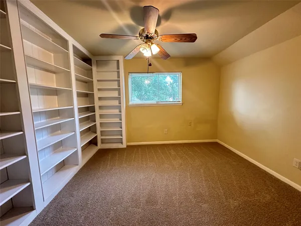 a view of an empty room with a window and a ceiling fan