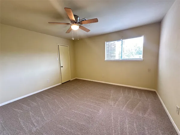 an empty room with a window and a fan