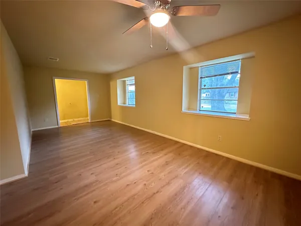 a view of an empty room with wooden floor and a window