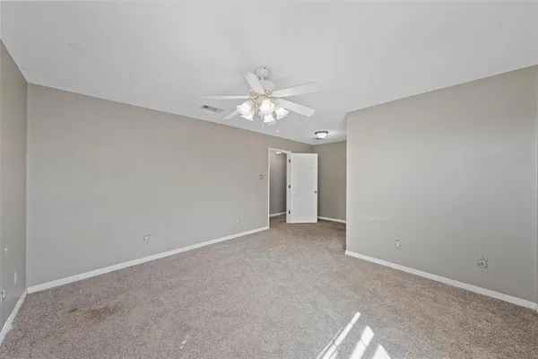 an empty room with a window and a chandelier fan