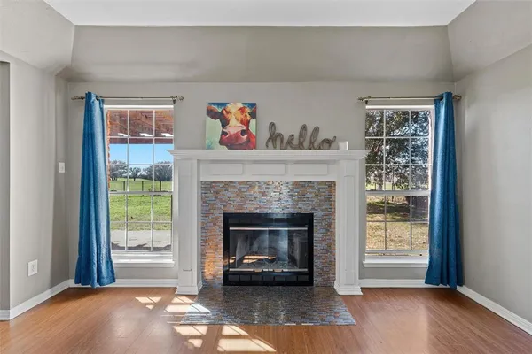 an empty room with wooden floor chandelier and windows