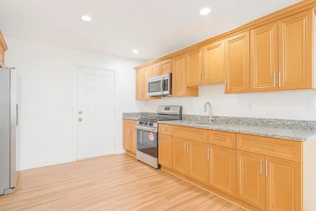 a kitchen with stainless steel appliances granite countertop a sink and cabinets with wooden floor