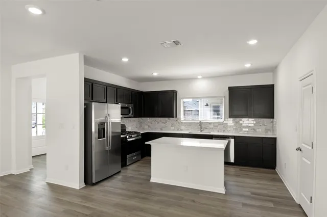 a kitchen with stainless steel appliances granite countertop a refrigerator and a stove top oven