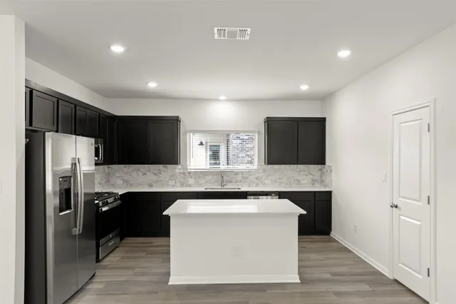 a kitchen with kitchen island stainless steel appliances a sink cabinets and a counter top space