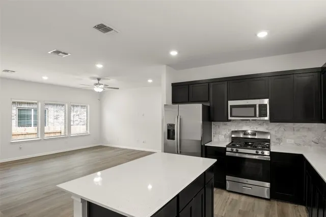 a kitchen with stainless steel appliances a stove a refrigerator a sink and white cabinets