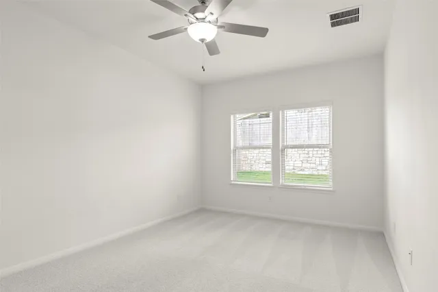 an empty room with windows and fan