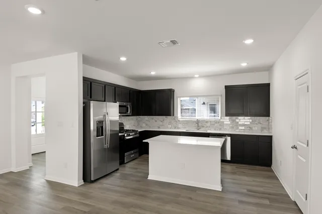 a kitchen with stainless steel appliances granite countertop a refrigerator and a stove top oven