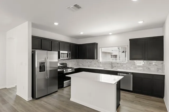 a kitchen with stainless steel appliances a stove refrigerator sink and cabinets