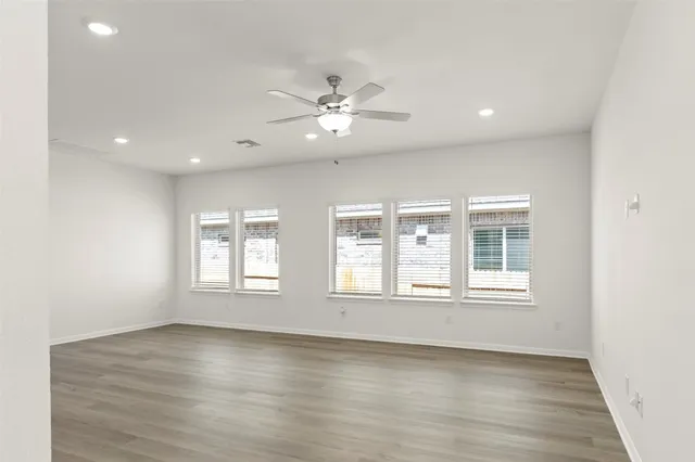 an empty room with wooden floor and windows with curtains