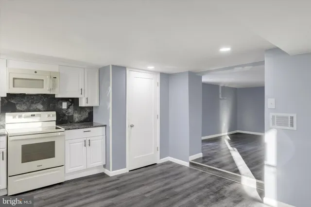 a view of kitchen with granite countertop cabinets and white appliances