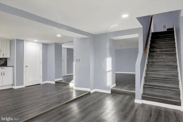 a view of an empty room with wooden floor and stairs