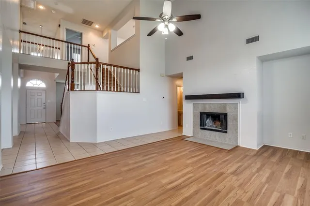 a view of an empty room with wooden floor fireplace and a window