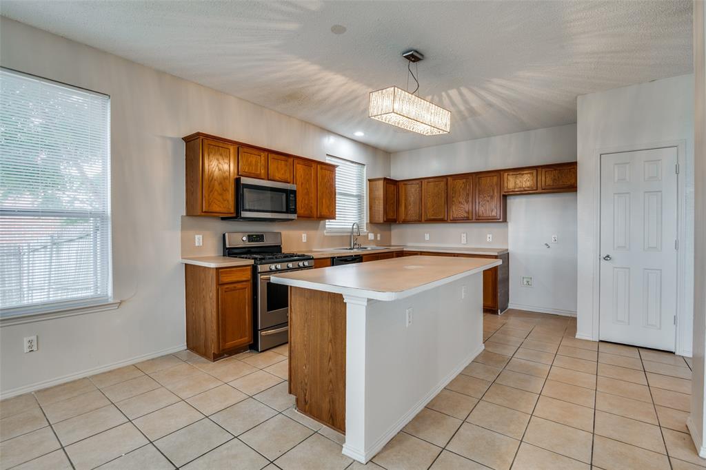2401 Redfield Drive Mesquite, TX 75181 - Photo 8 of 25 a kitchen with stainless steel appliances granite countertop a large stove a sink dishwasher and a refrigerator with wooden cabinets