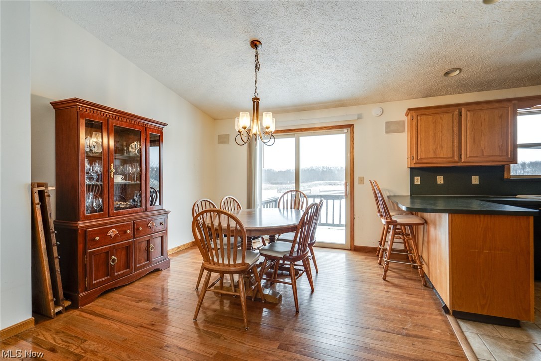 5303 Laubert Road Atwater, OH 44201 - Photo 12 of 37 Dining room with a chandelier, vaulted ceiling, light hardwood / wood-style floors, and a textured ceiling