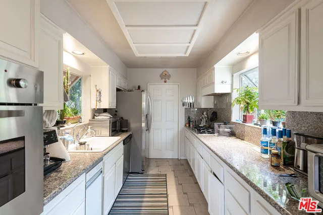 a large kitchen with stainless steel appliances granite countertop a sink a stove and a refrigerator