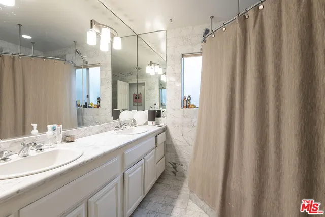 a bathroom with a double vanity sink mirror and shower