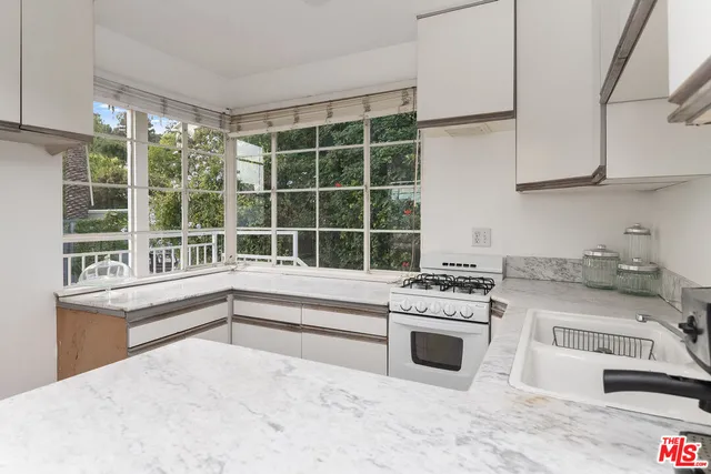 a kitchen with stainless steel appliances granite countertop a stove a sink and a white cabinets