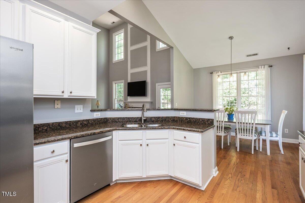 714 Continental Drive Durham, NC 27712 - Photo 11 of 34 a kitchen with granite countertop a stove a sink and white cabinets with wooden floor