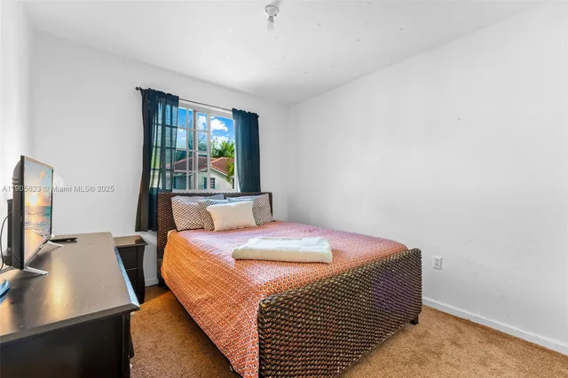 a bedroom with a bed and a flat tv screen on dresser