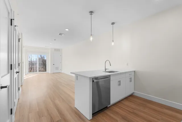 a view of a kitchen with sink and dishwasher with wooden floor